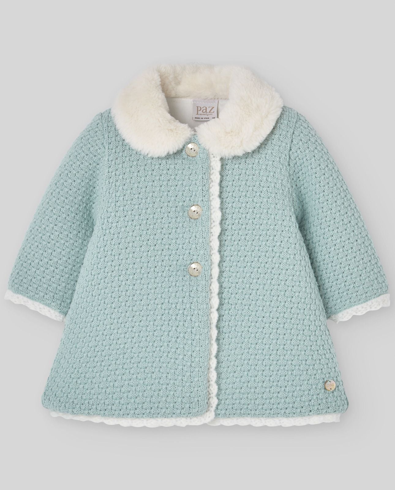 A baby girl is wearing a blue coat with a white fur collar.;A baby girl is wearing a light blue coat with a white collar.;A baby 's clothes are laid out on a white surface