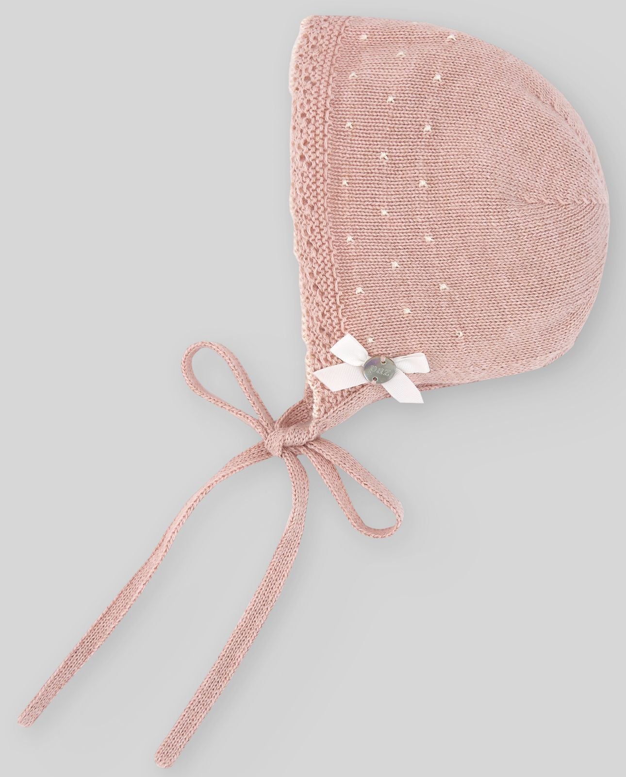 A pink knitted hat with a tie around the neck;A pink knitted hat with a white flower on it