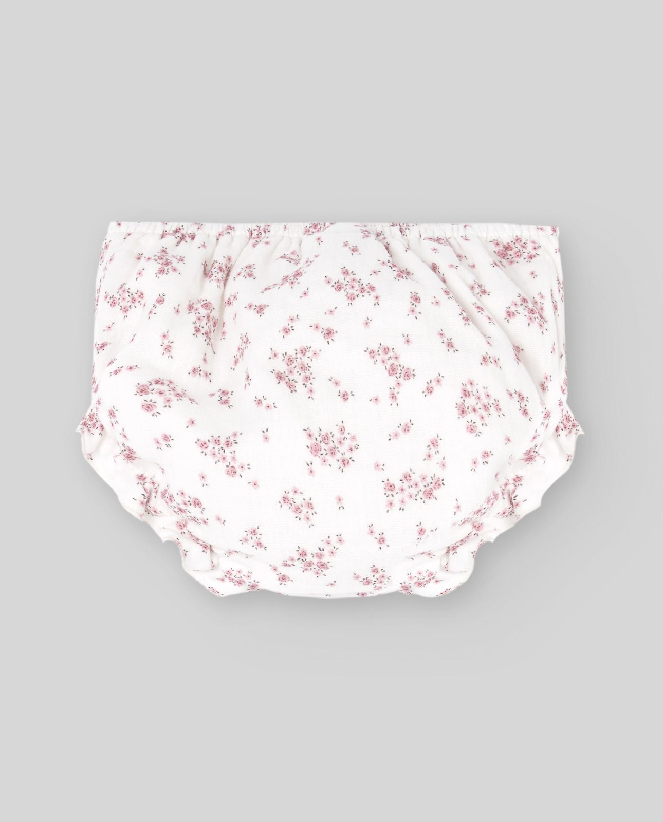 A baby girl is wearing a white dress with pink flowers on it.;A baby girl is wearing a white dress with pink flowers on it.