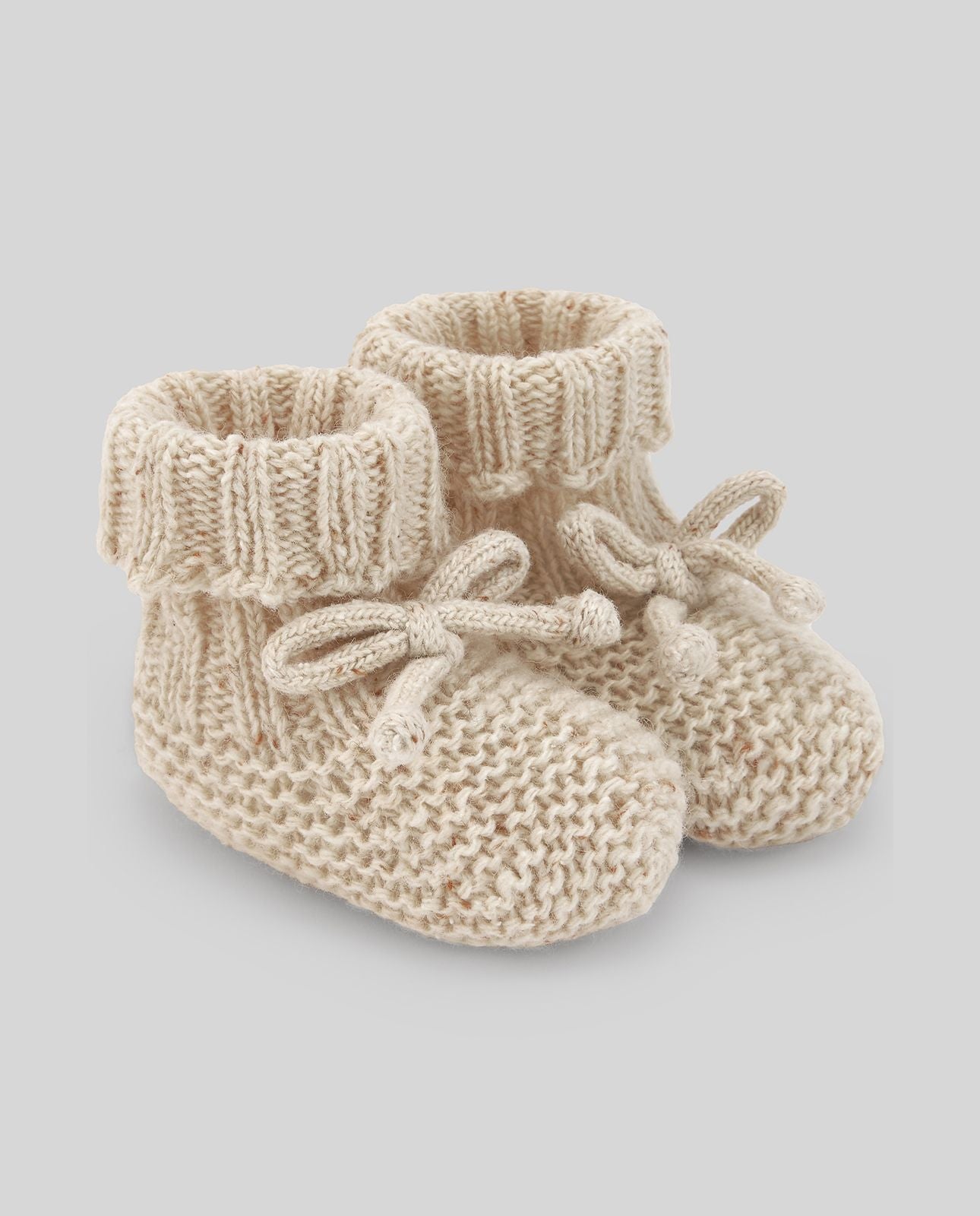 A pair of knitted baby booties with a bow on a white background.;A pair of knitted baby booties with a bow on a white background.