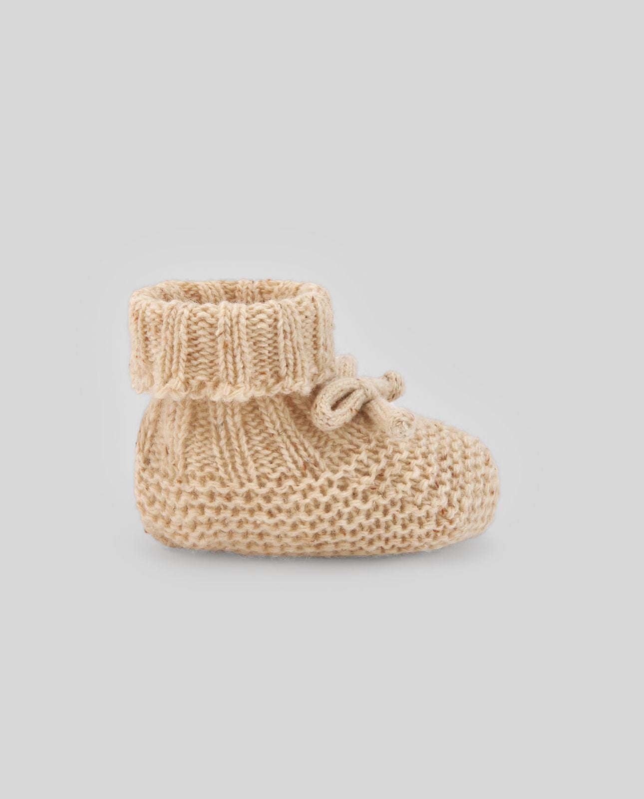 A pair of knitted baby booties with a bow on a white background.;A pair of knitted baby booties with a bow on a white background.