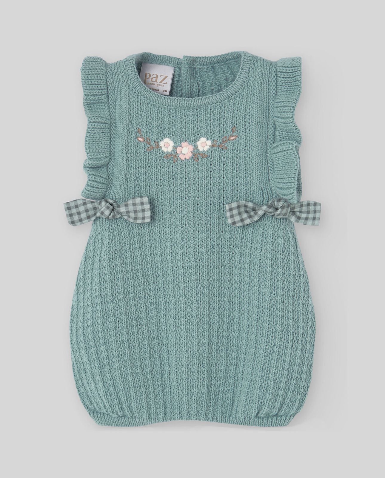 A baby girl is wearing a green knitted dress with flowers on it.;A light blue sweater with ruffles on the sleeves