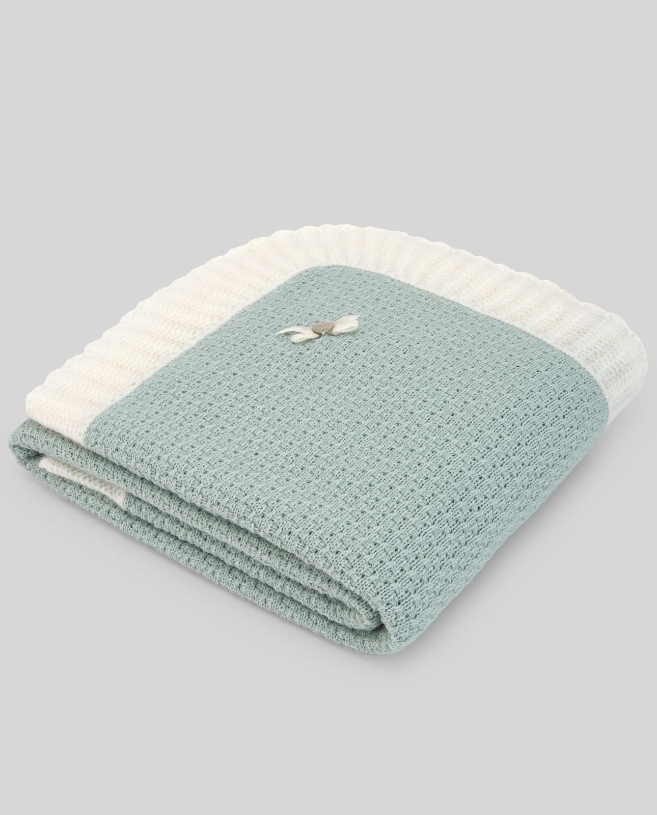 A close up of a knitted blanket with a flower on it.;A blue and white blanket with a bow on it