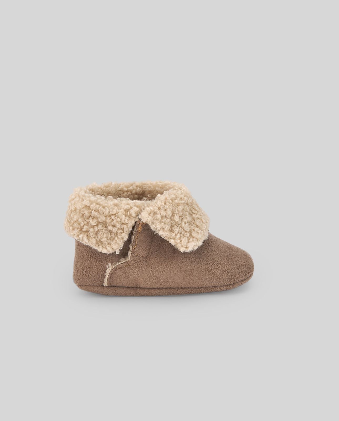 A pair of brown slippers with a furry cuff on a white background.;A pair of brown baby shoes with a furry collar on a white background.