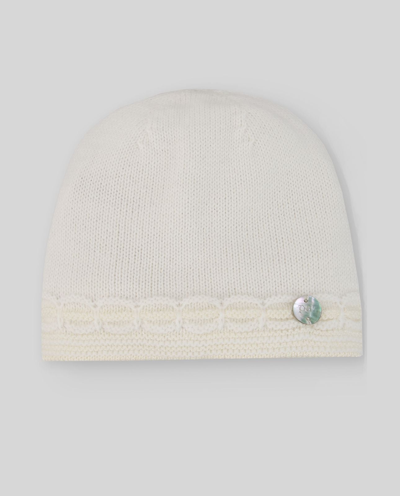 A white knitted hat with a button on the side.;A white beanie with a rhinestone on it