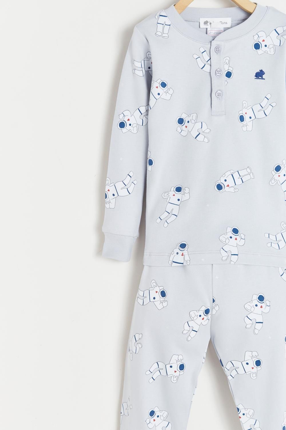 A pajama set with a pattern of sheep on it is hanging on a hanger.;The back of a pajama set with sheep on it is hanging on a hanger.;A child 's pajama set with sheep on it is hanging on a wooden hanger.
