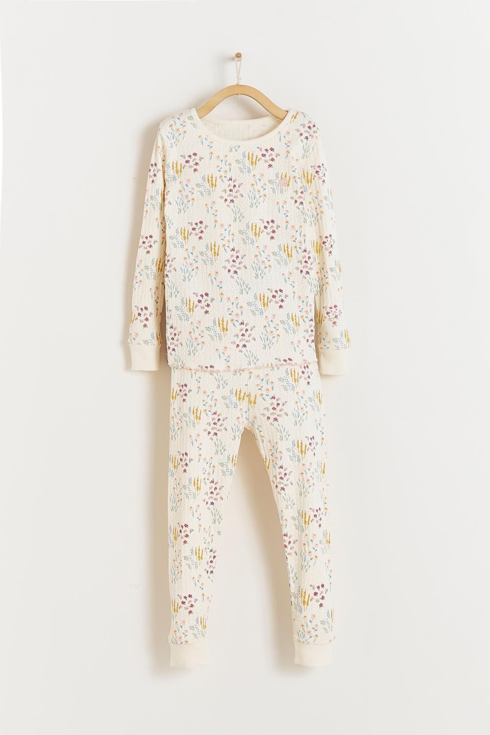 A white shirt with a floral print is hanging on a wooden hanger.;A close up of a fabric with a floral pattern on it.;A white pajama set with a floral print is hanging on a hanger.;A white pajama set with a floral pattern is hanging on a hanger.;A pair of white pants with a floral print is hanging on a wooden hanger.;A white pajama set with a floral print is hanging on a hanger.
