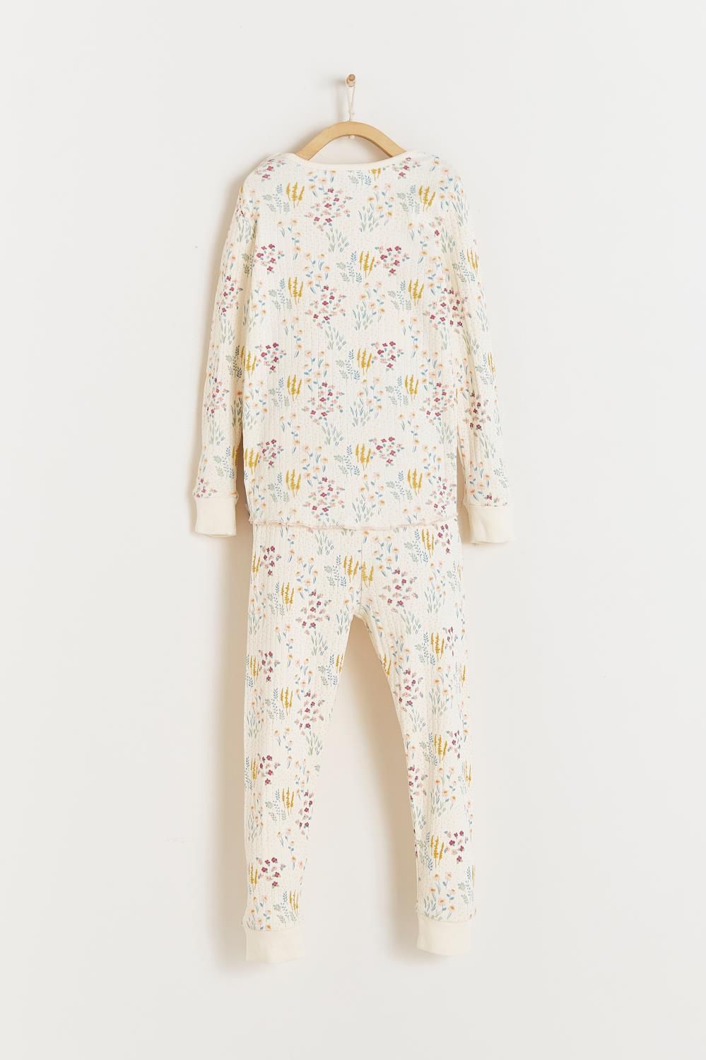 A white shirt with a floral print is hanging on a wooden hanger.;A close up of a fabric with a floral pattern on it.;A white pajama set with a floral print is hanging on a hanger.;A white pajama set with a floral pattern is hanging on a hanger.;A pair of white pants with a floral print is hanging on a wooden hanger.;A white pajama set with a floral print is hanging on a hanger.
