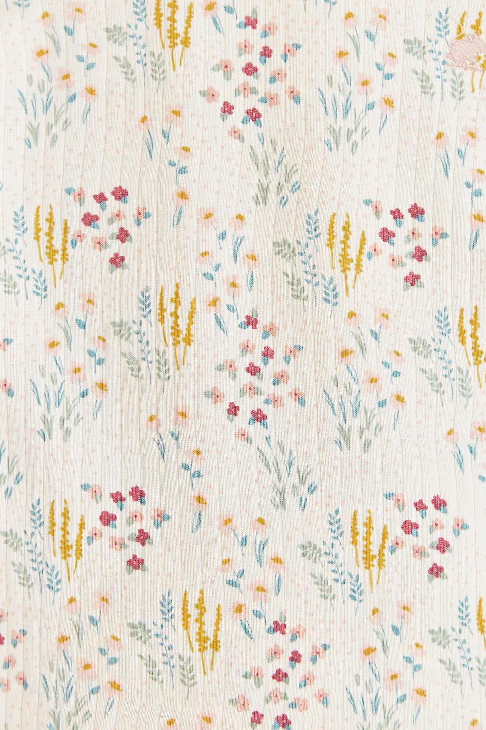 A white shirt with a floral print is hanging on a wooden hanger.;A close up of a fabric with a floral pattern on it.;A white pajama set with a floral print is hanging on a hanger.;A white pajama set with a floral pattern is hanging on a hanger.;A pair of white pants with a floral print is hanging on a wooden hanger.;A white pajama set with a floral print is hanging on a hanger.