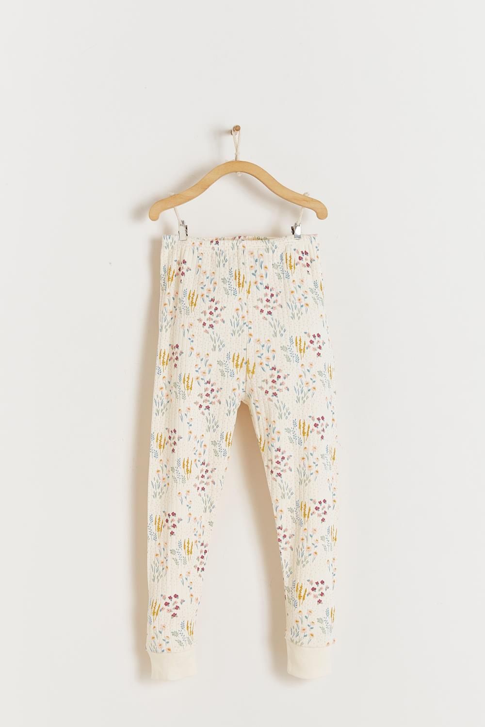 A white shirt with a floral print is hanging on a wooden hanger.;A close up of a fabric with a floral pattern on it.;A white pajama set with a floral print is hanging on a hanger.;A white pajama set with a floral pattern is hanging on a hanger.;A pair of white pants with a floral print is hanging on a wooden hanger.;A white pajama set with a floral print is hanging on a hanger.