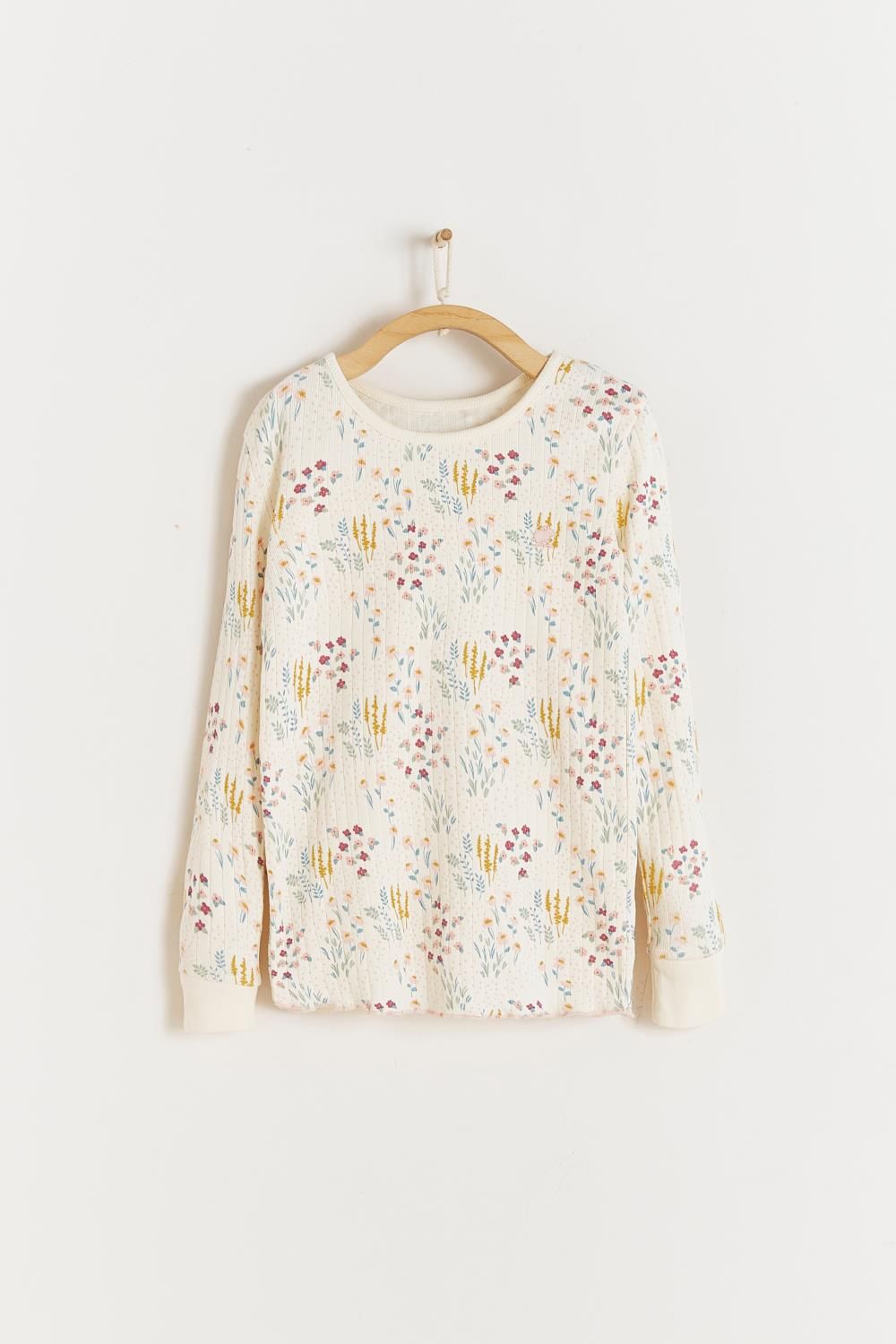 A white shirt with a floral print is hanging on a wooden hanger.;A close up of a fabric with a floral pattern on it.;A white pajama set with a floral print is hanging on a hanger.;A white pajama set with a floral pattern is hanging on a hanger.;A pair of white pants with a floral print is hanging on a wooden hanger.;A white pajama set with a floral print is hanging on a hanger.