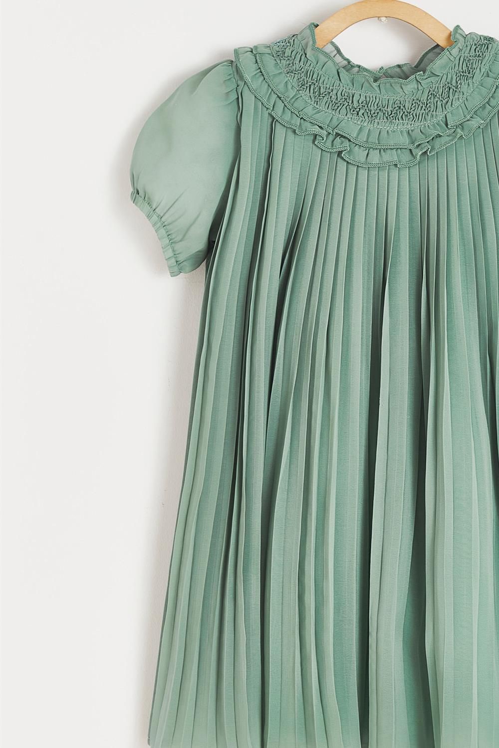 A green pleated dress is hanging on a wooden hanger.;A green dress with short sleeves is hanging on a hanger.;A close up of a green pleated skirt with ruffles on the bottom.