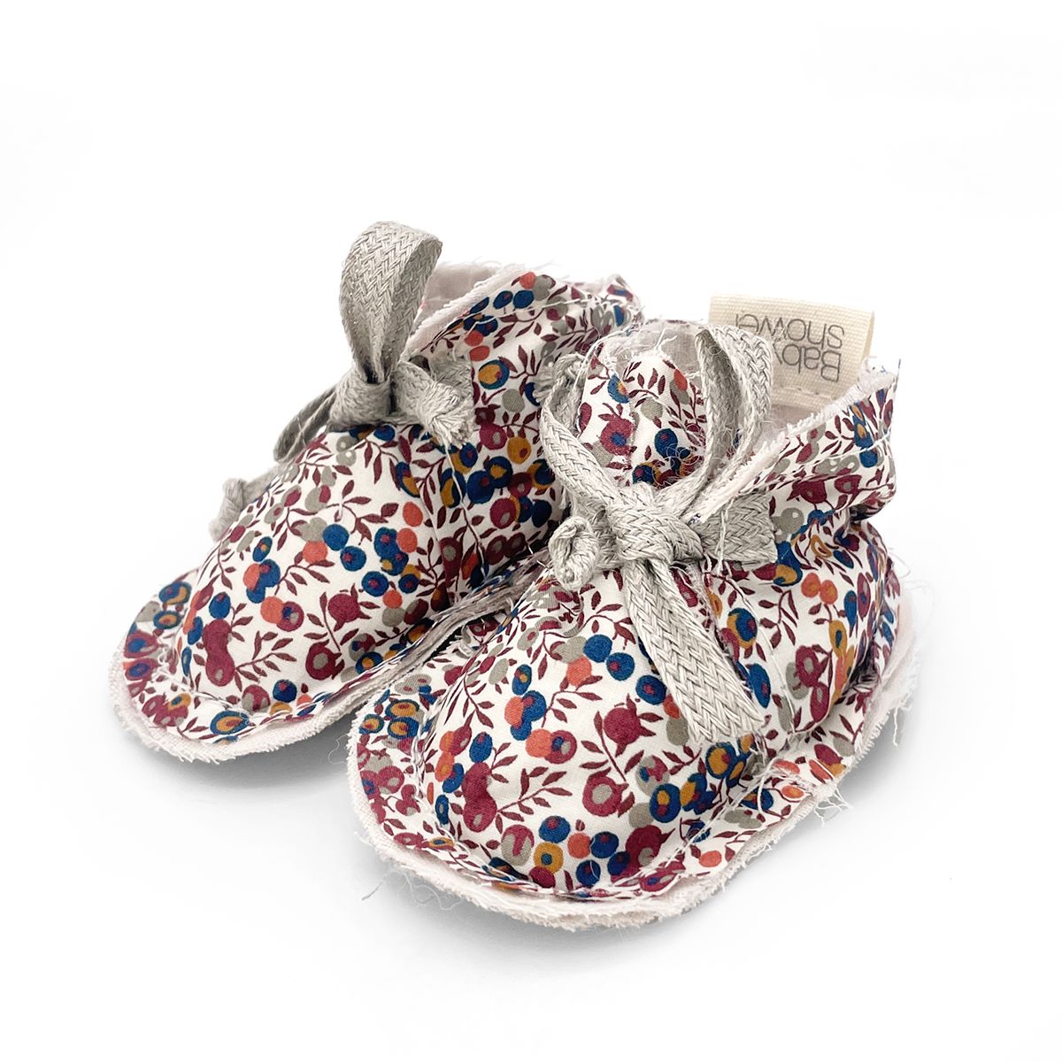 A pair of baby shoes with a floral pattern on a white background.