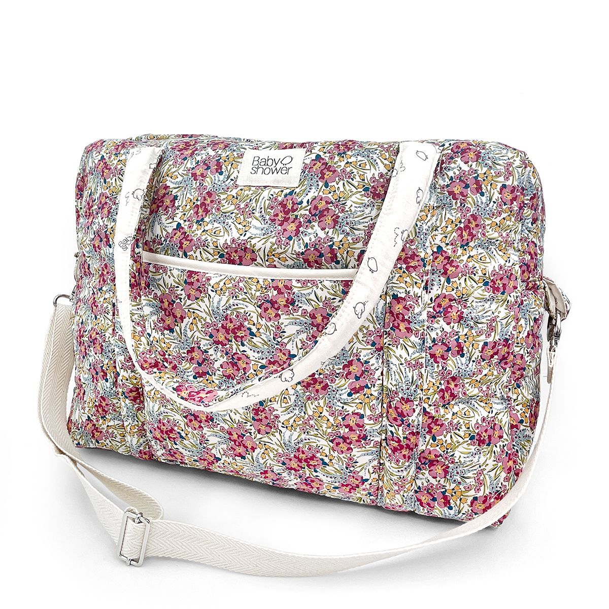 A floral diaper bag with a white strap on a white background.