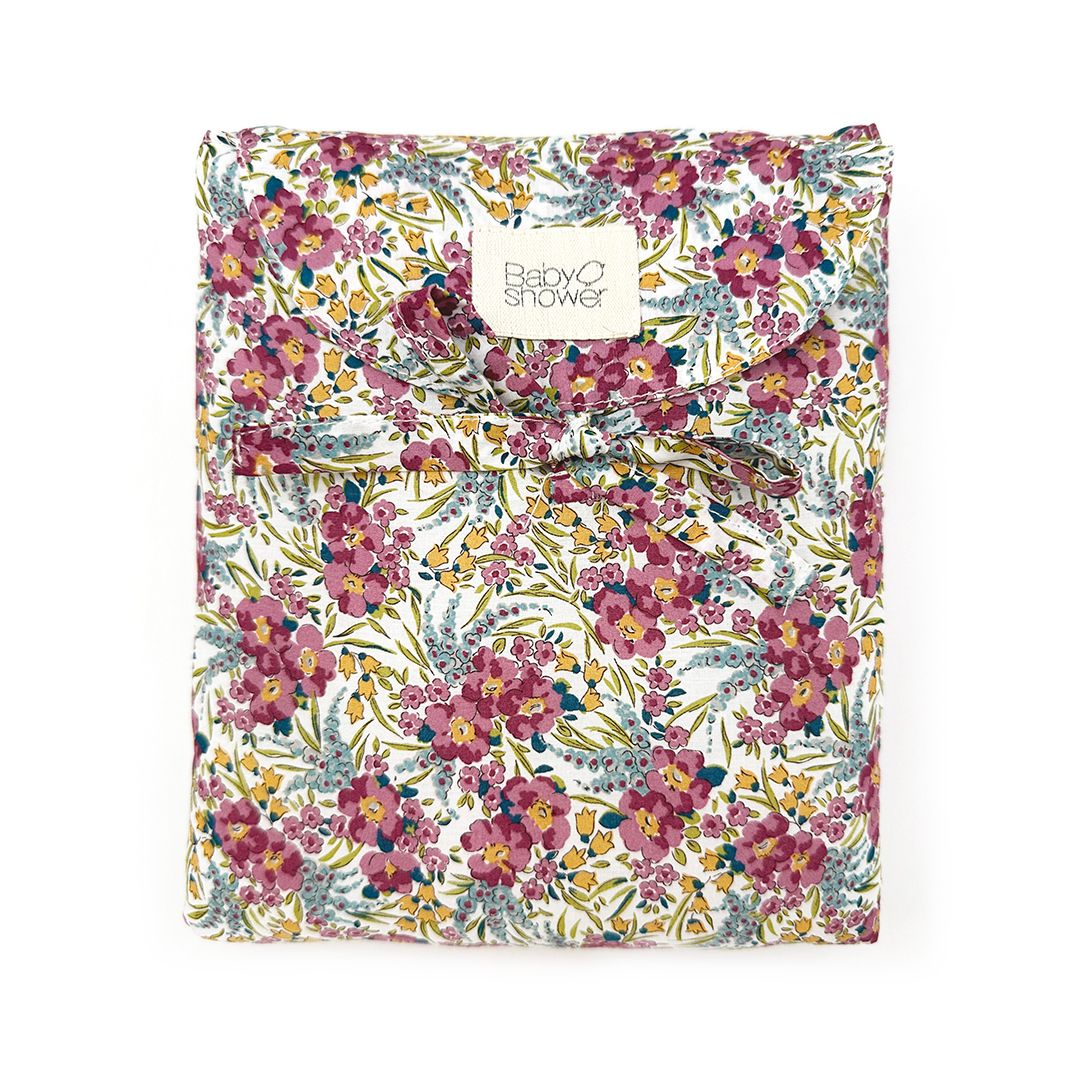 A white blanket with blue and yellow flowers on it.;A blanket with a floral pattern on it is on a white background.;A gray blanket with a bow on it on a white background.;A notebook with a floral pattern on it is on a white background.;A bag with a floral pattern on it is on a white background.;A pink waffle blanket with a white label on it is tied with a bow.