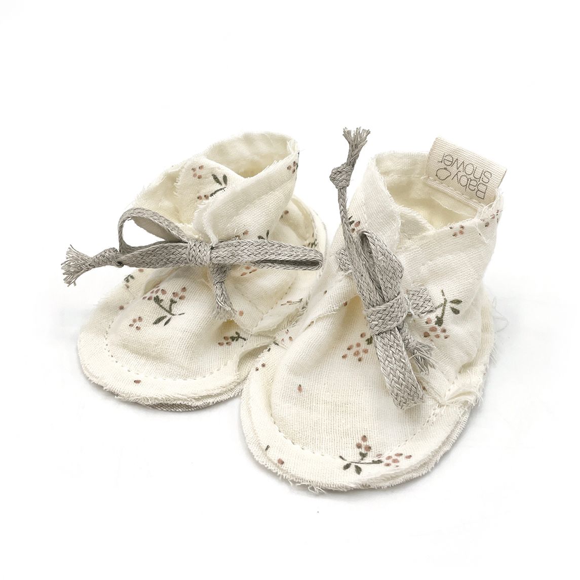 A pair of white baby shoes on a white background.