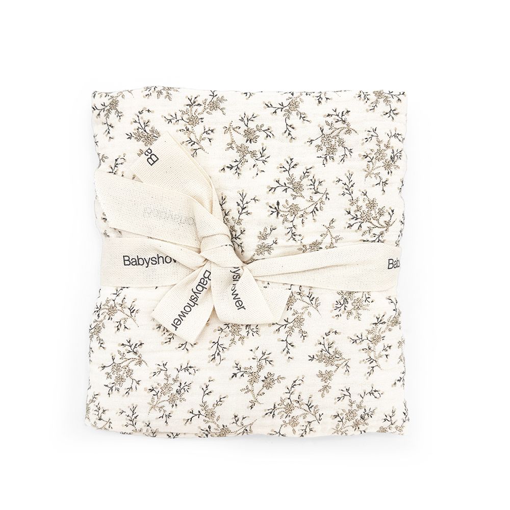 A white blanket with a floral pattern and a white ribbon tied around it.