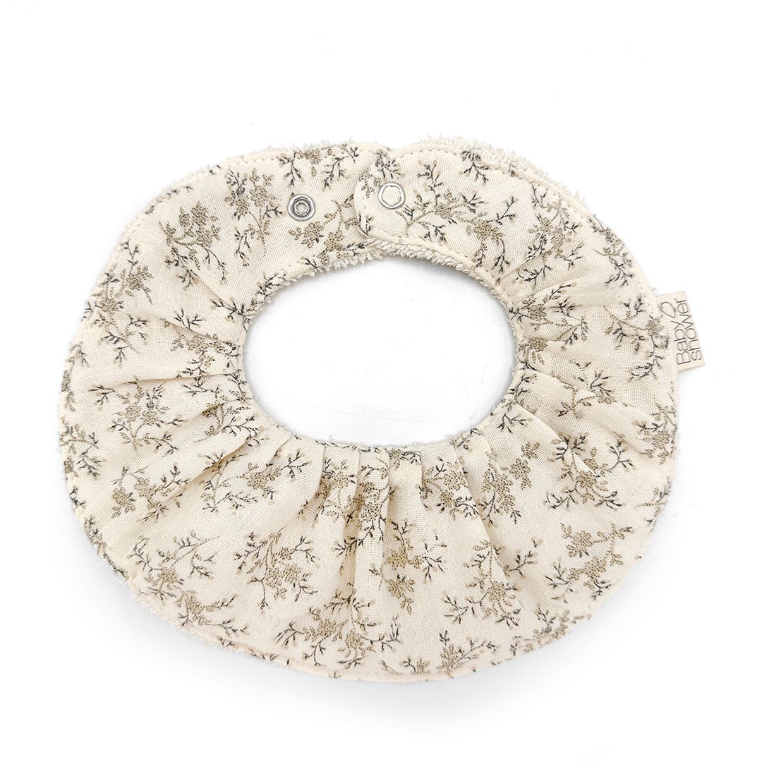 A white bib with a floral pattern on it is on a white background.