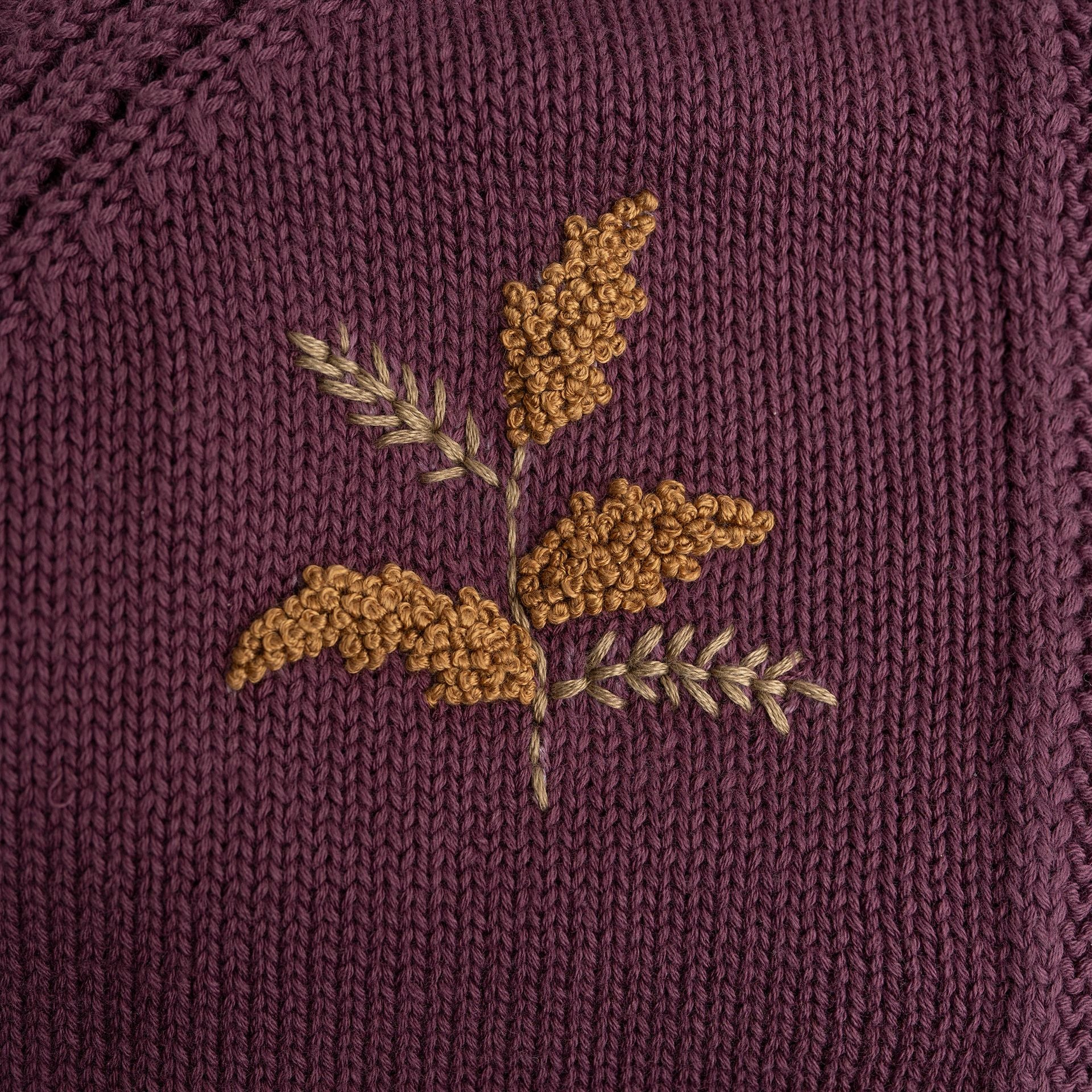 A baby girl is wearing a purple cardigan with flowers embroidered on it.;A purple sweater with ruffles on the bottom is on a white background.;A close up of a purple sweater with a flower embroidered on it.;A close up of a purple sweater with yellow flowers embroidered on it.