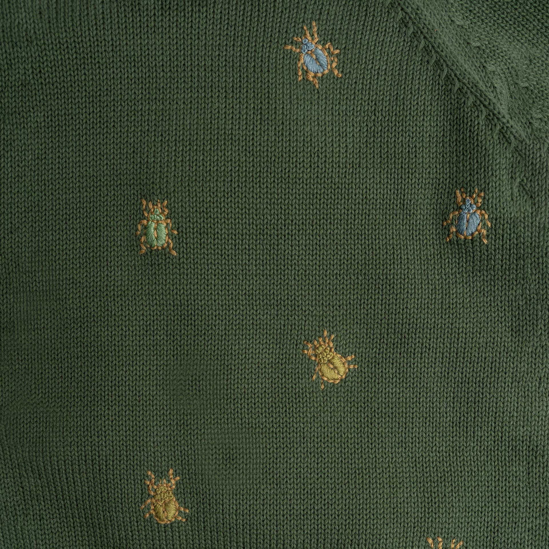 A young boy wearing a green sweater and blue pants is standing in front of a brick wall.;A green sweater with gold bees embroidered on it;A green sweater with long sleeves on a white background;A close up of a green sweater with bees embroidered on it.