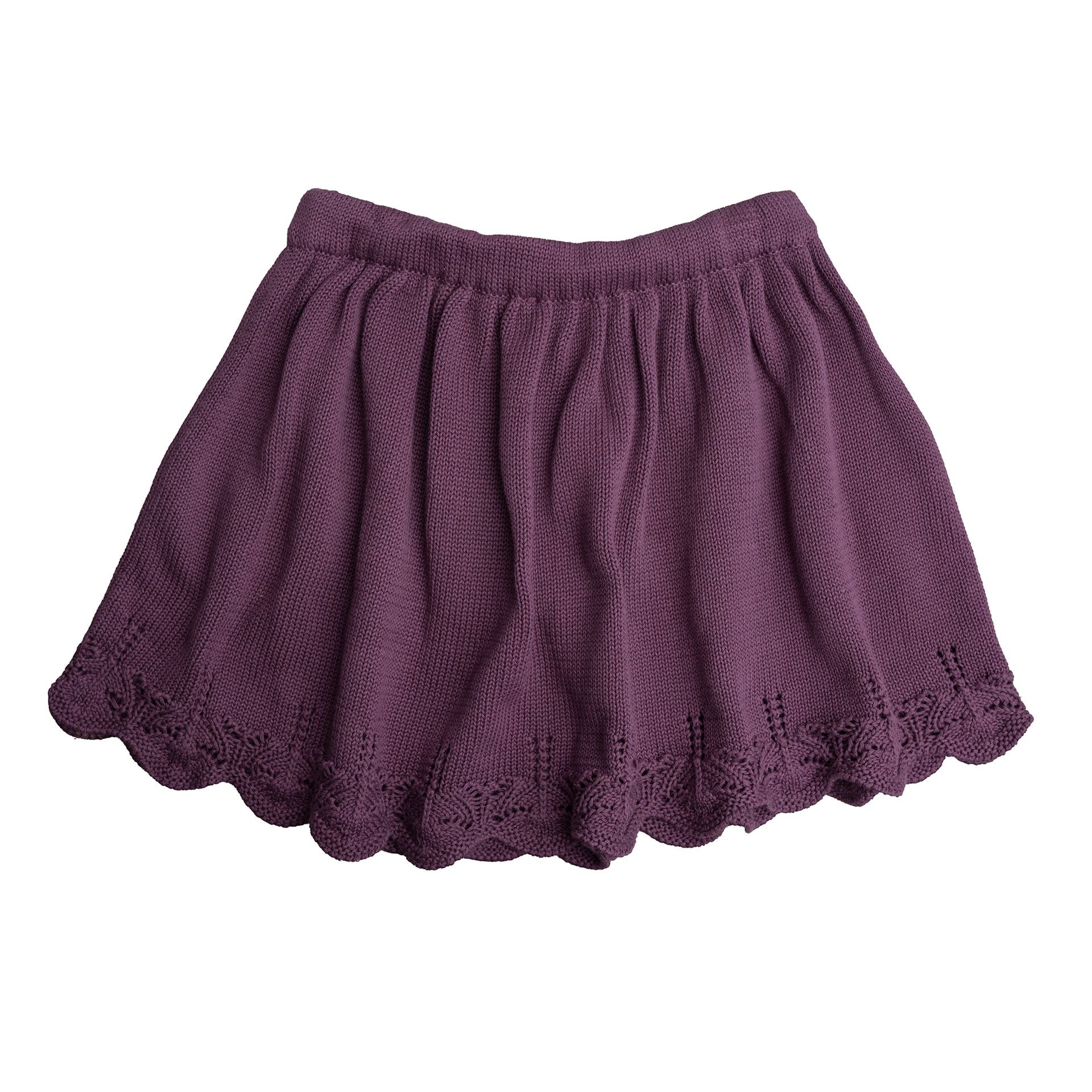 A close up of a purple knitted blanket with a lace trim.;A purple knitted skirt is on a white background.;A little girl is standing on a dirt road in the woods.