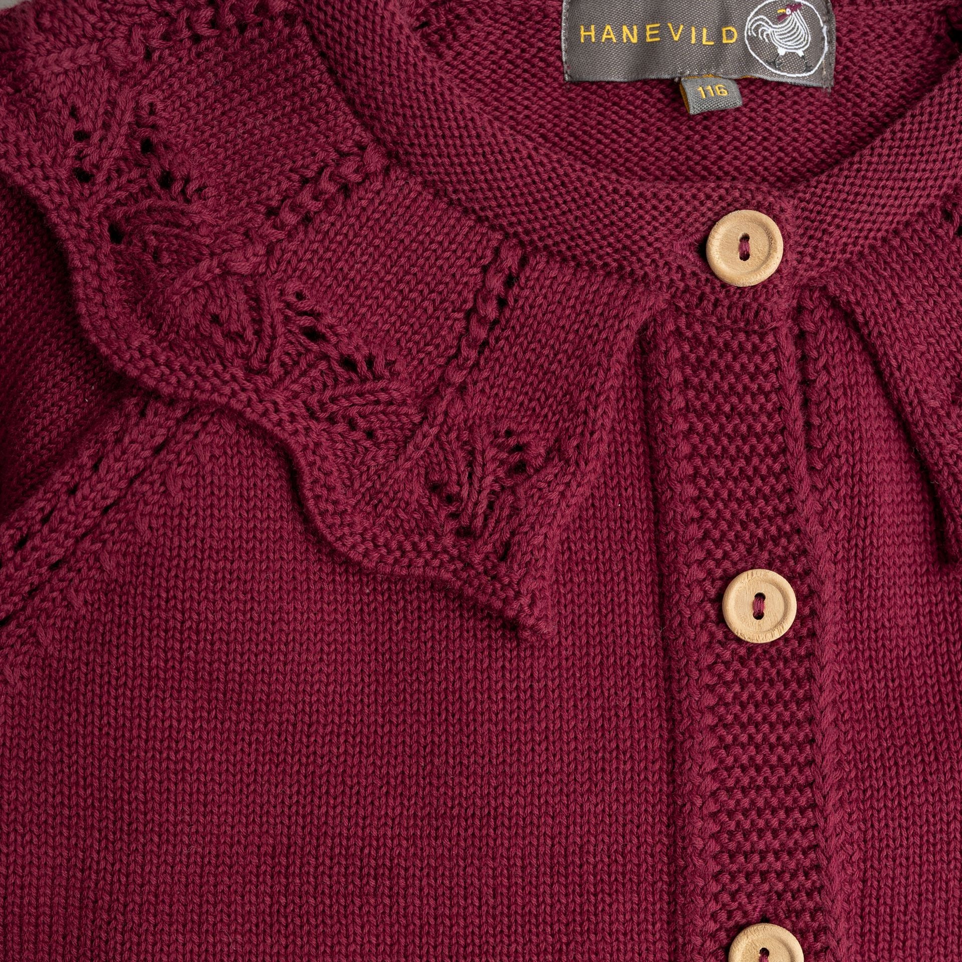 A baby girl is wearing a burgundy cardigan with ruffles and buttons.;A red sweater with long sleeves and a ruffled collar;A close up of a purple sweater with wooden buttons.;A little girl is wearing a red sweater and looking at the camera.