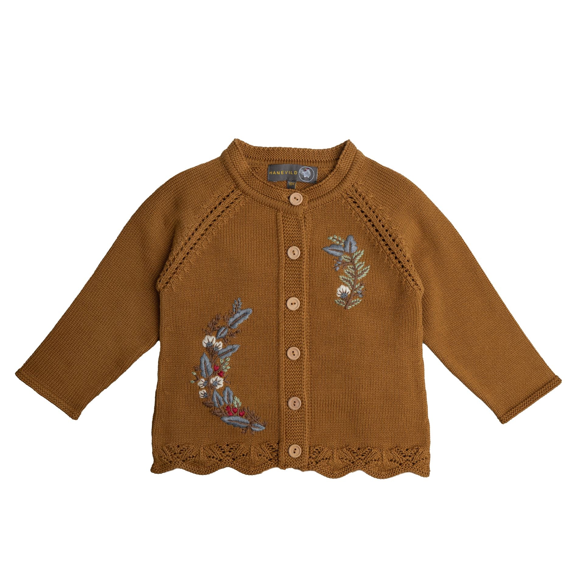 A little girl wearing a brown sweater and a white hat is standing in the snow.;A baby girl is wearing a brown cardigan with embroidery on it.;A close up of a sweater with a floral embroidery on it.;A close up of a sweater with a flower embroidered on it.