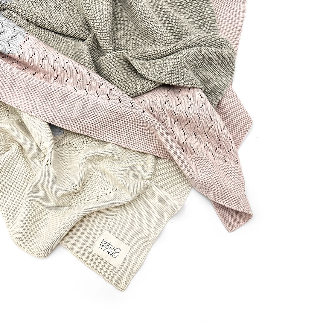 A close up of a knitted blanket on a white background.