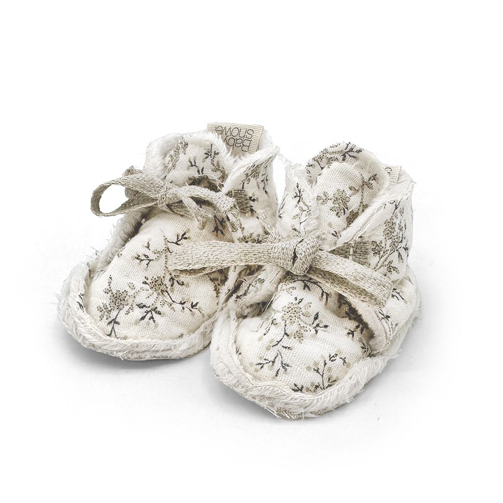 A pair of white baby shoes on a white background.