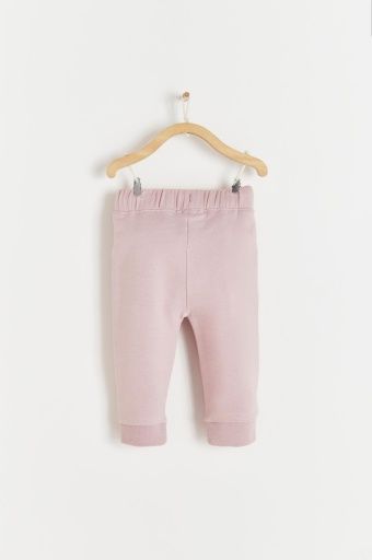 A pair of pink sweatpants hanging on a wooden hanger.;A pair of pink pants hanging on a wooden hanger.;A pair of pink sweatpants hanging on a wooden hanger;A close up of a pink fabric texture.