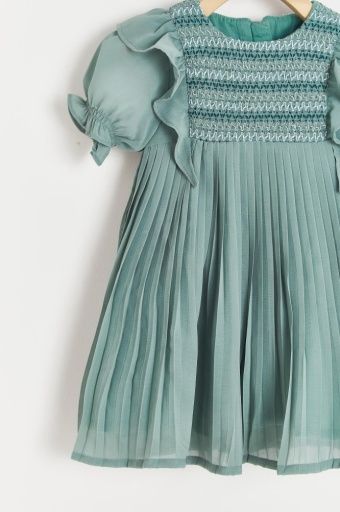 A green pleated dress is hanging on a wooden hanger.;A green dress with short sleeves is hanging on a hanger.;A close up of a green pleated skirt with ruffles on the bottom.