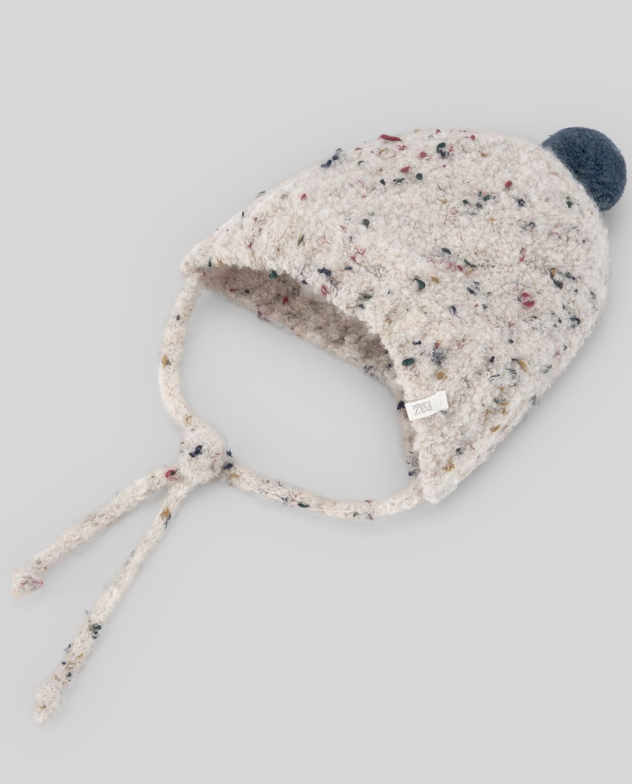 A white knitted hat with a blue pom pom on a white background.;A white hat with a blue pom pom on top
