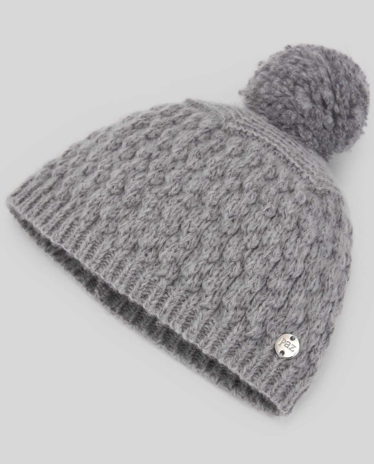A grey knitted hat with a pom pom on top;A grey knitted hat with a pom pom on top;A red knitted hat with a large red pom pom;A red knitted hat with a pom pom on top