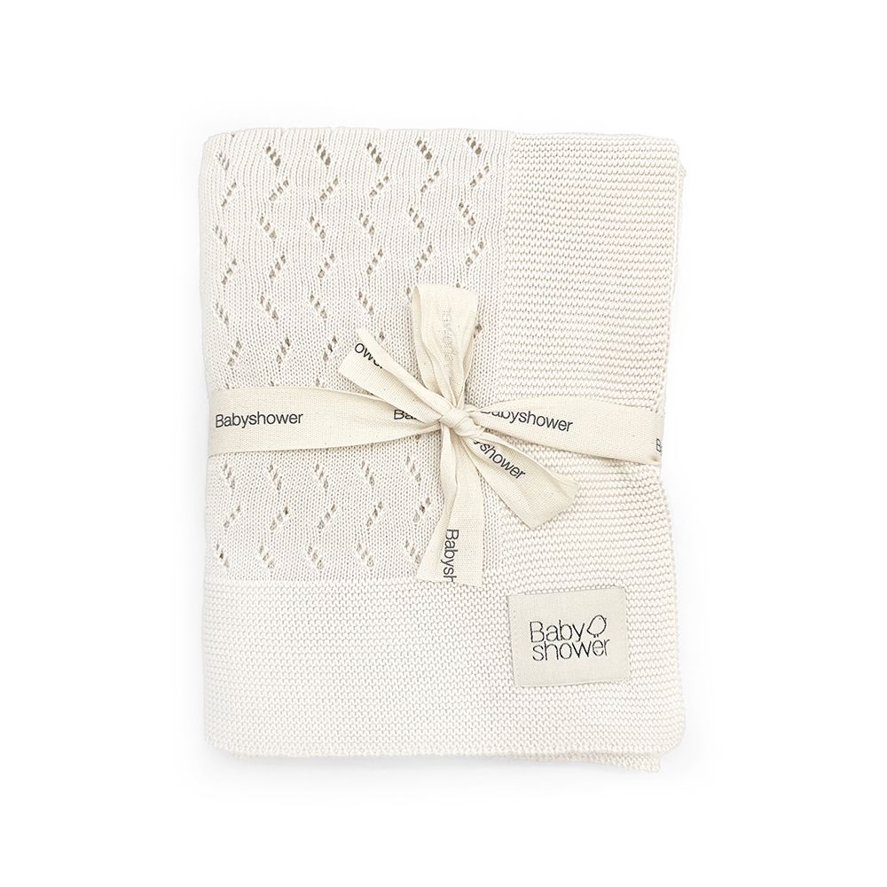 A white blanket with a ribbon tied around it on a white background.